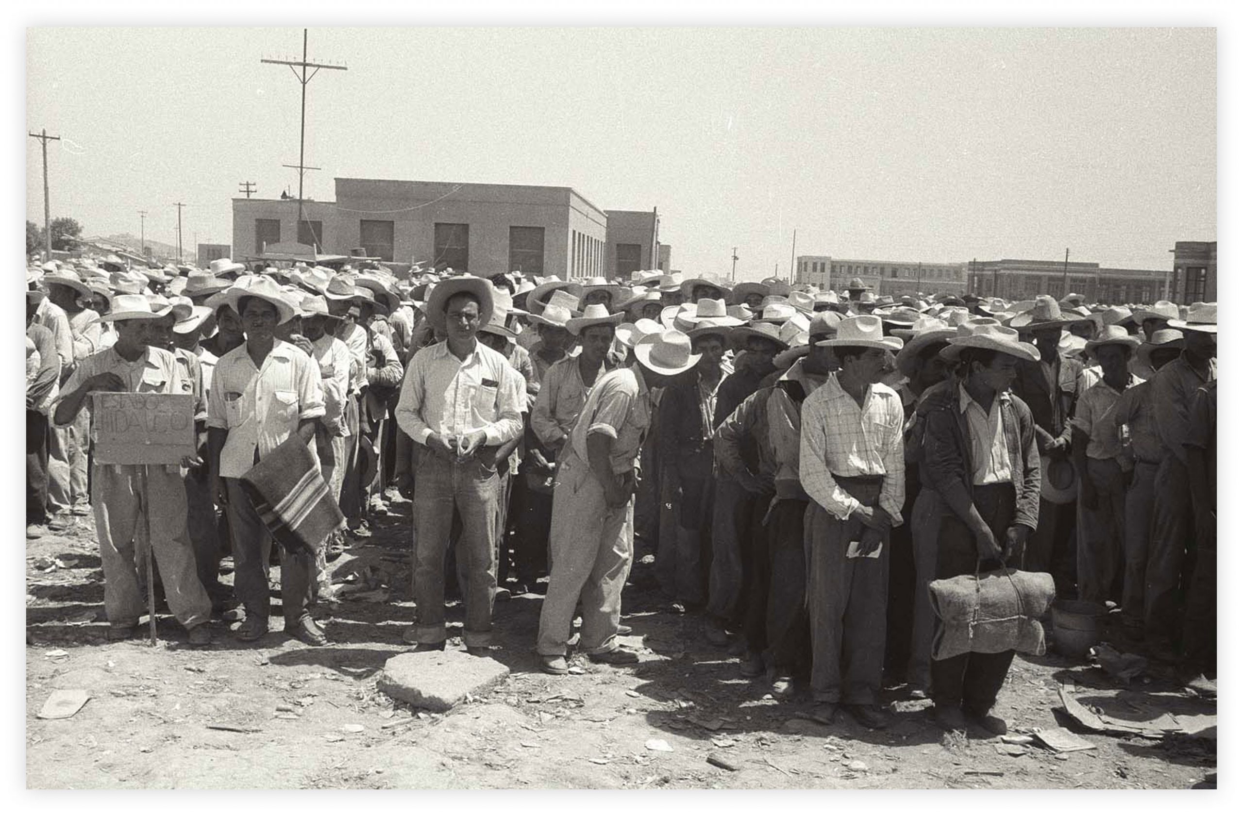 Line up of Mexicans several with suitcases waiting to be called up for processing at the Control Station in Monterrey, Mex. Each line represents a particular area of Mexico from which the braceros come and they are processed by groups.