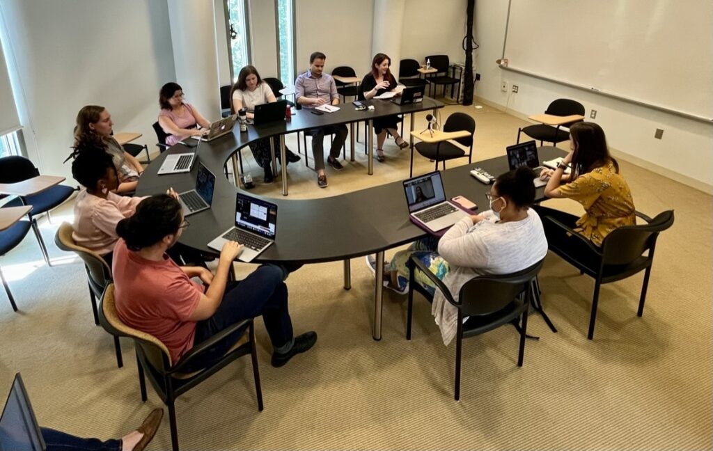 RRCHNM graduate students, faculty, and staff working together around a table.